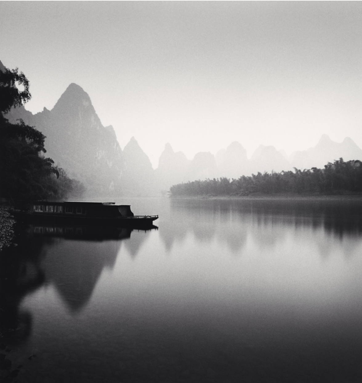 Foggy landscape with a river in the foreground and a mountain in the distance