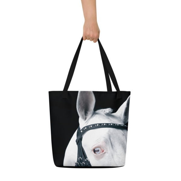 Woman's hand holding a Large bag with a close up of the head and eye of a white horse