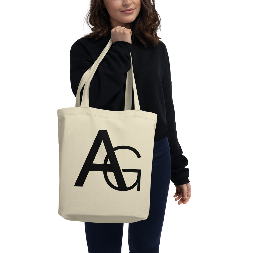 Woman holding a Medium beige tote bag with AG initials on front side