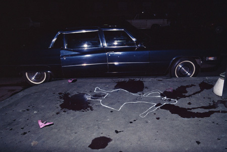 Chalk outline of a woman's silhouette on a road, near a stopped car