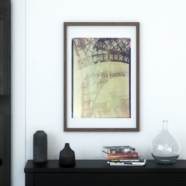 Framed print of a collage print showing a detail of the Eiffel Tower pillar, hanging above a console table