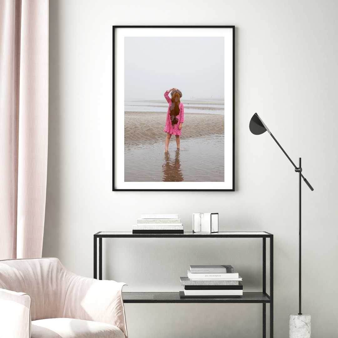 A woman on a foggy beach holds seaweed to hide her face