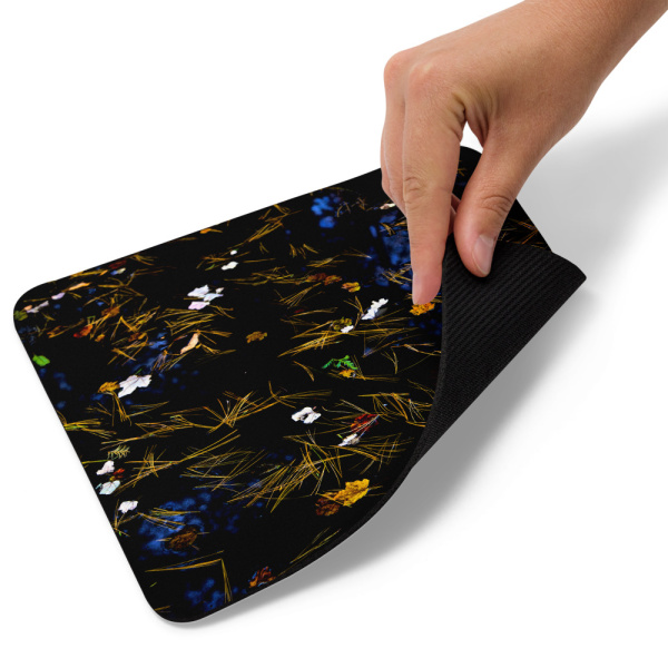 A mouse pad with a photograph of a pond with petals and leaves floating on it