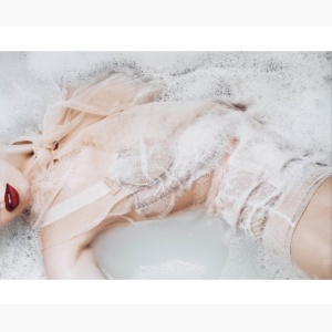 Woman in lingerie half submersed in a milky bath