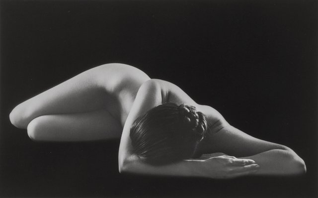 Naked female model, laying on the floor with her face hidden from view