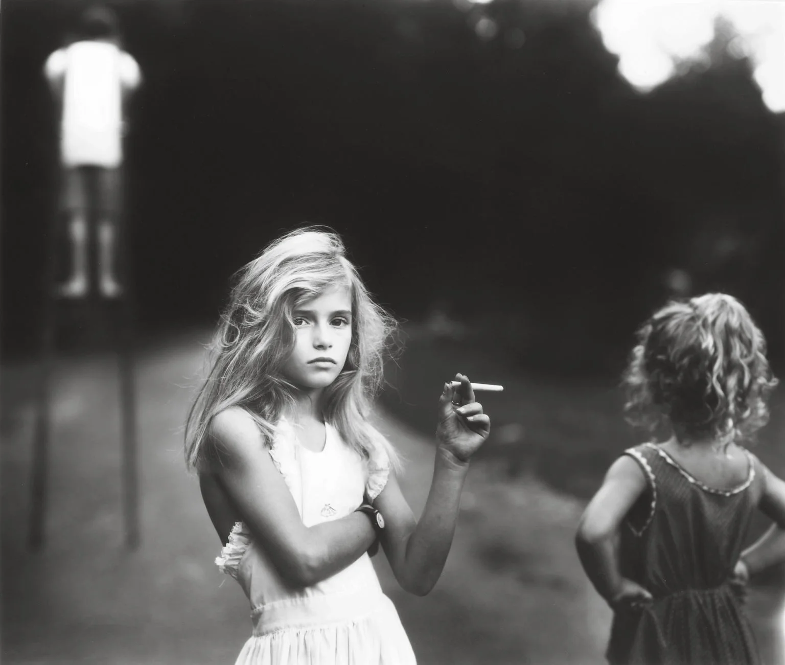 A young girl holding a candy cigarette as if she's smoking