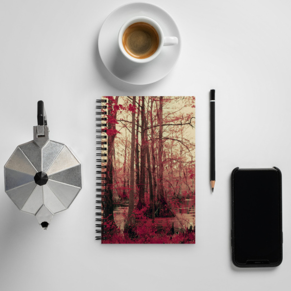 Notebook on a table, next to a coffee cup, pen and cell phone