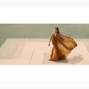 Woman in a flowy dress walking by a swimming pool,