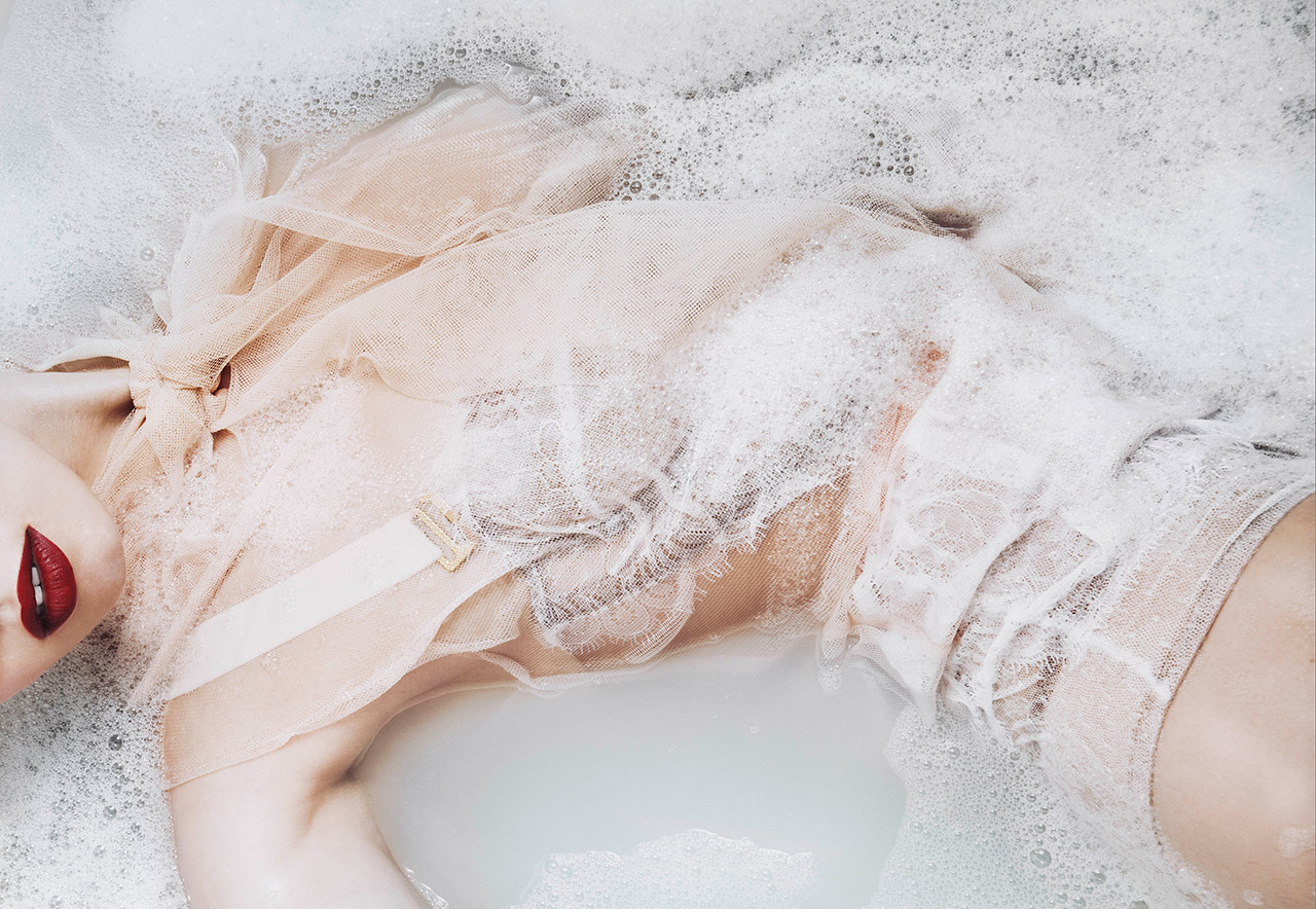 Woman in lingerie half submersed in a milky bath