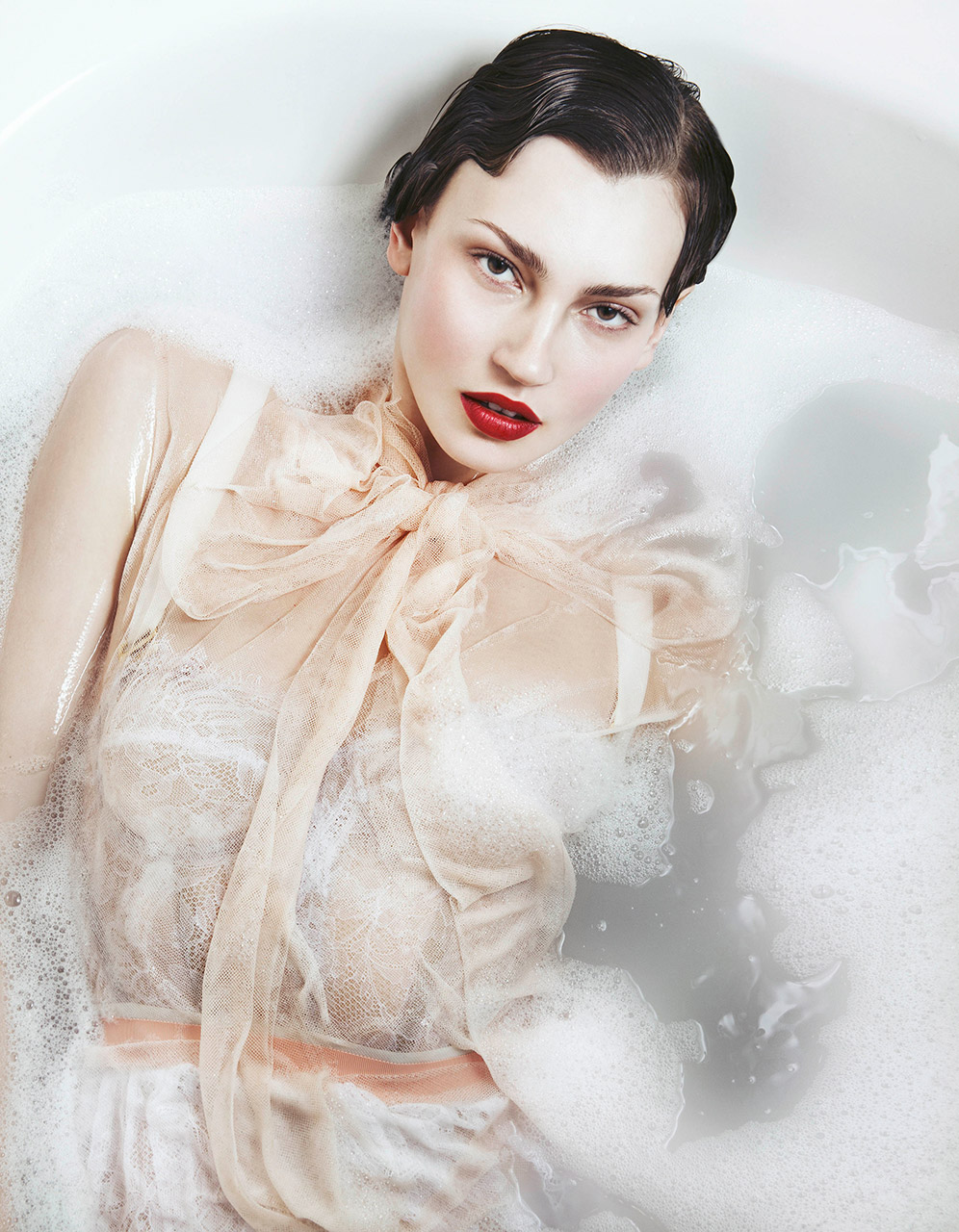 Woman in lingerie half submersed in a milky bath