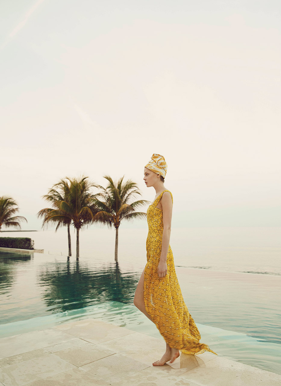 Limited edition print of a woman in a long dress, walking by a pool, with palm trees in the background