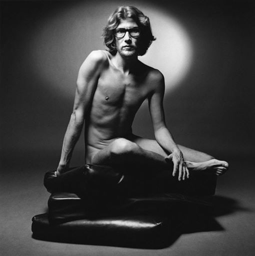 Fashion designer Yves Saint Laurent, naked, sitting on leather pouches on the floor