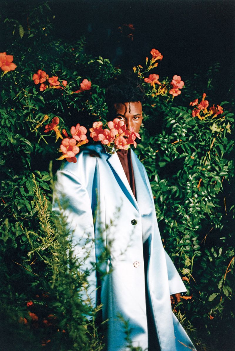 A young Black man standing in a flowery garden 