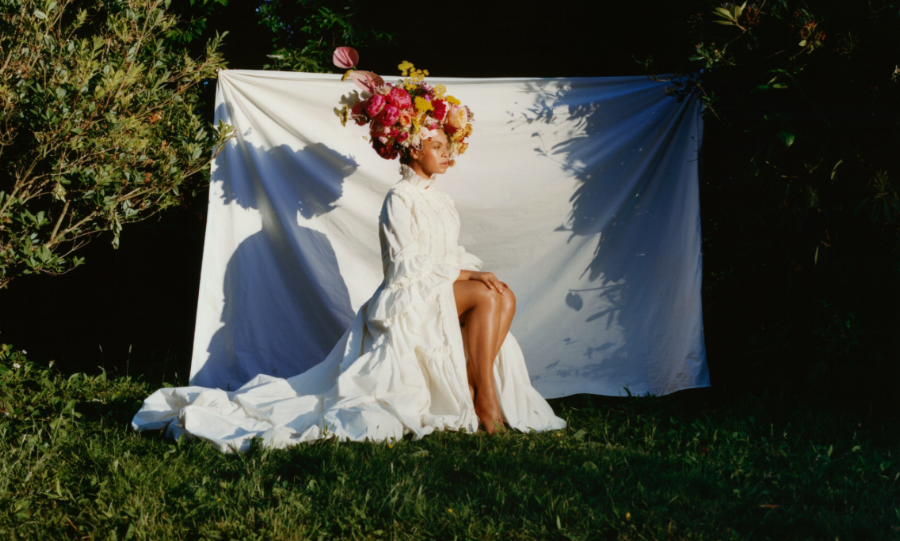Beyonce sitting against a sheet in the middle of a lush green garden