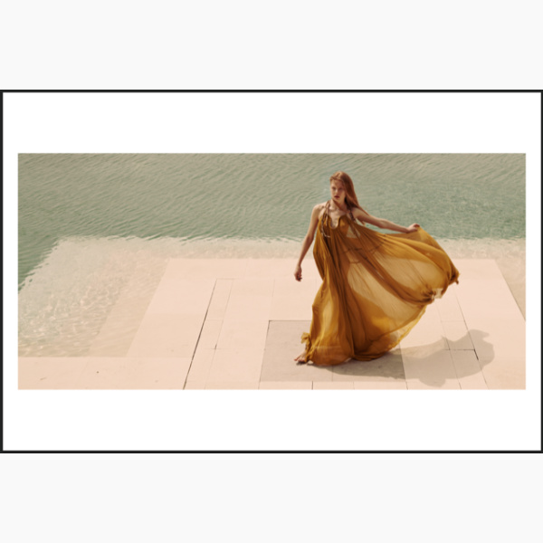 Woman in a long flowy dress walking by a pool