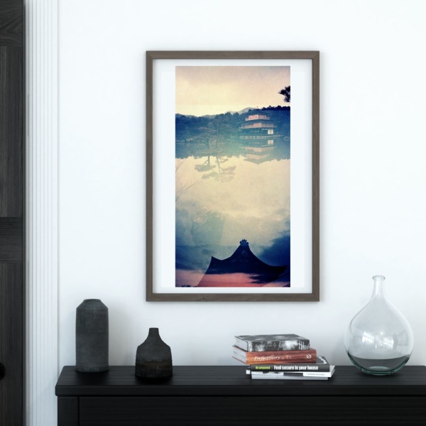 Framed print of a collage print showing a Japanese temple reflected in a pond, hanging above a console table