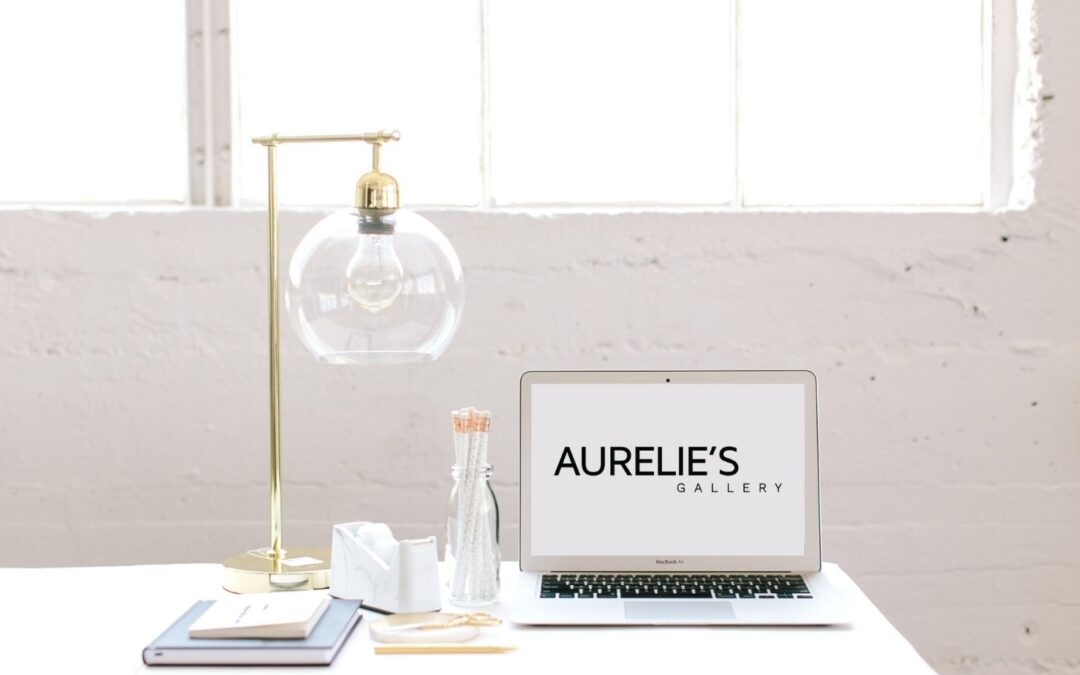 Laptop on a desk, with Aurelie's Gallery logo on its screen