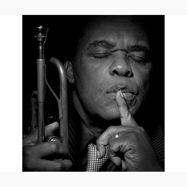 Freddie Hubbard holding his trumpet, with his eyes closed, listening to music