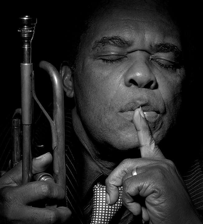Freddie Hubbard holding his saxophone and listening to music with his eyes closed