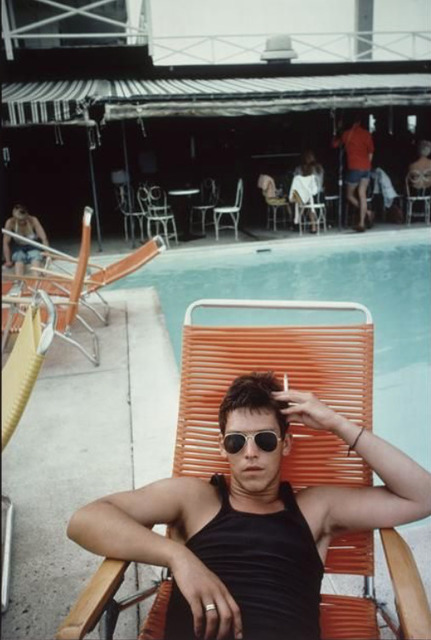 Young man sitting by a pool