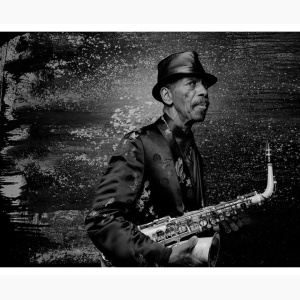 Ornette Coleman holding his saxophone in front of an abstract painting