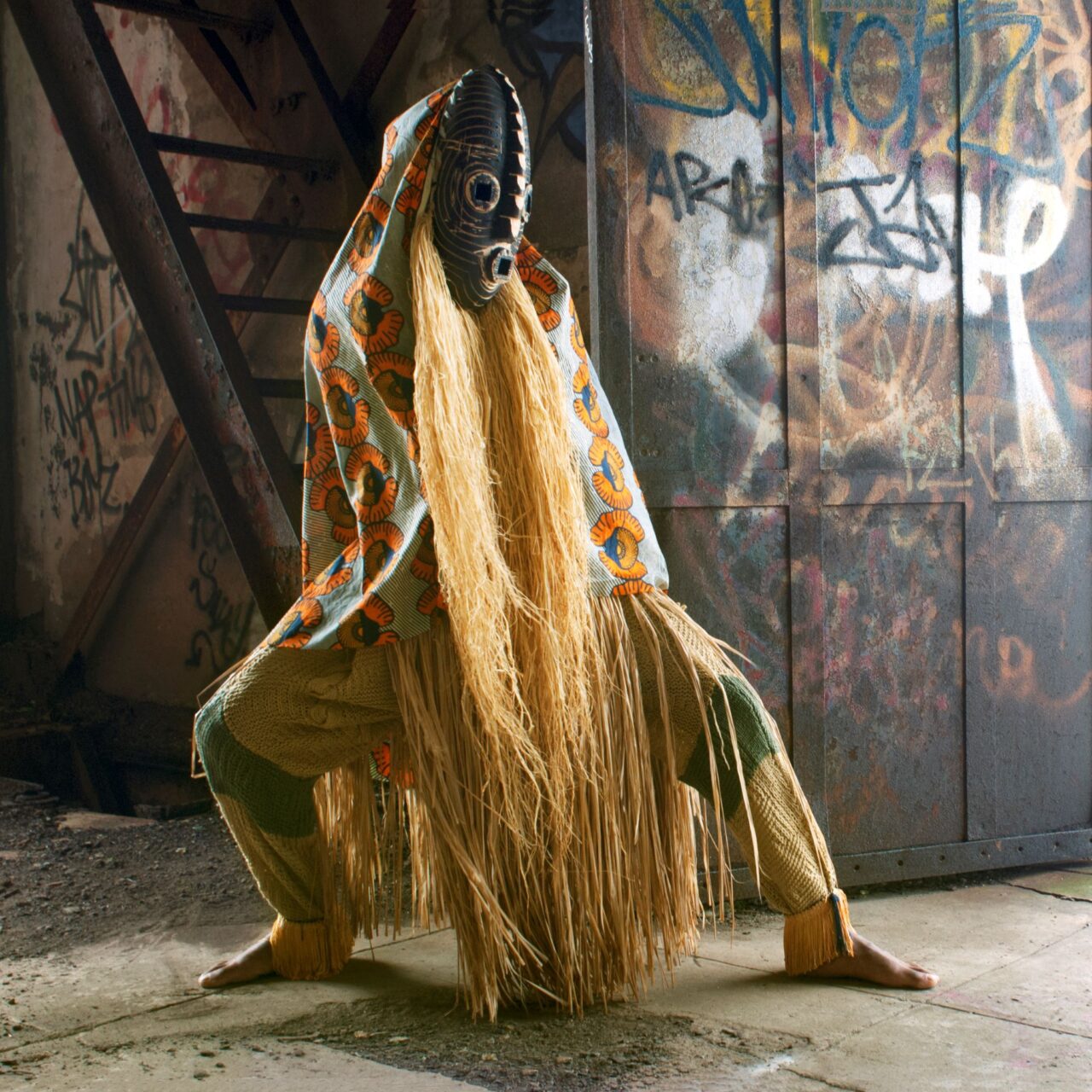 Limited edition print of a mysterious figure shrouded in a traditional African costume and hidden by a mask standing in an abandoned building