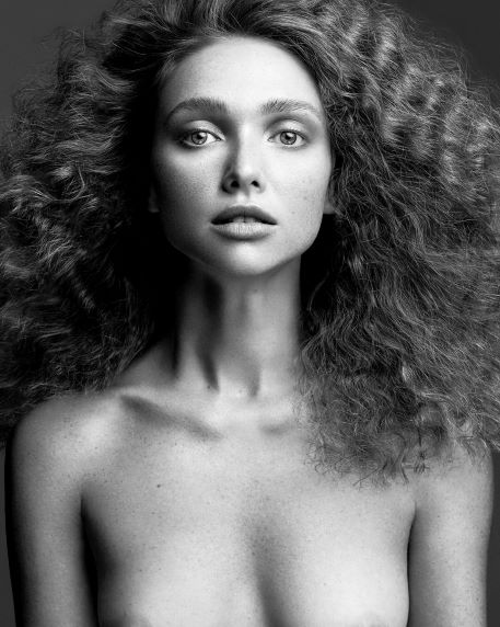 Portrait of a woman, topless, with wild hair, looking straight in the camera