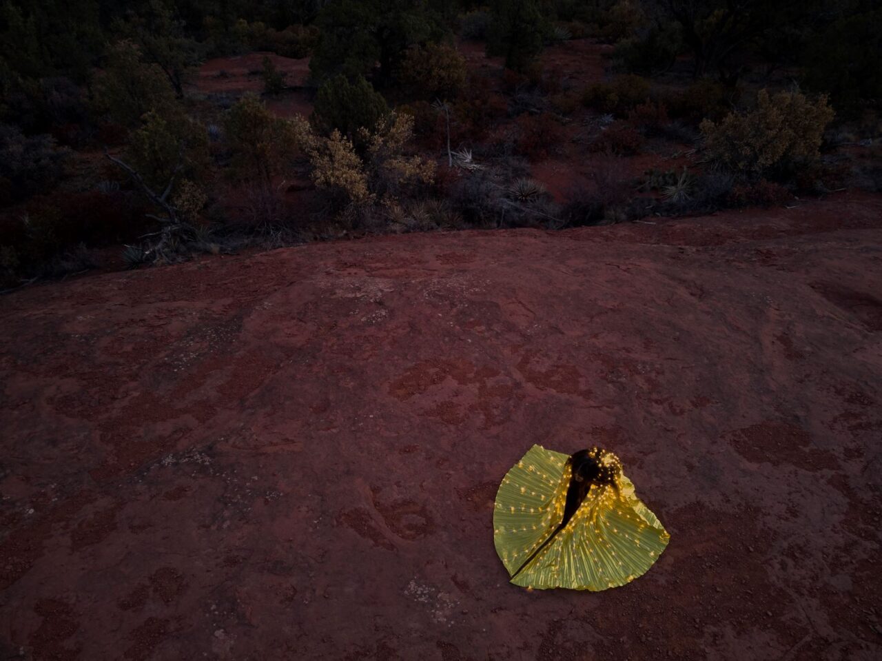 Woman in a lighted dress dancing on rocks in a desert