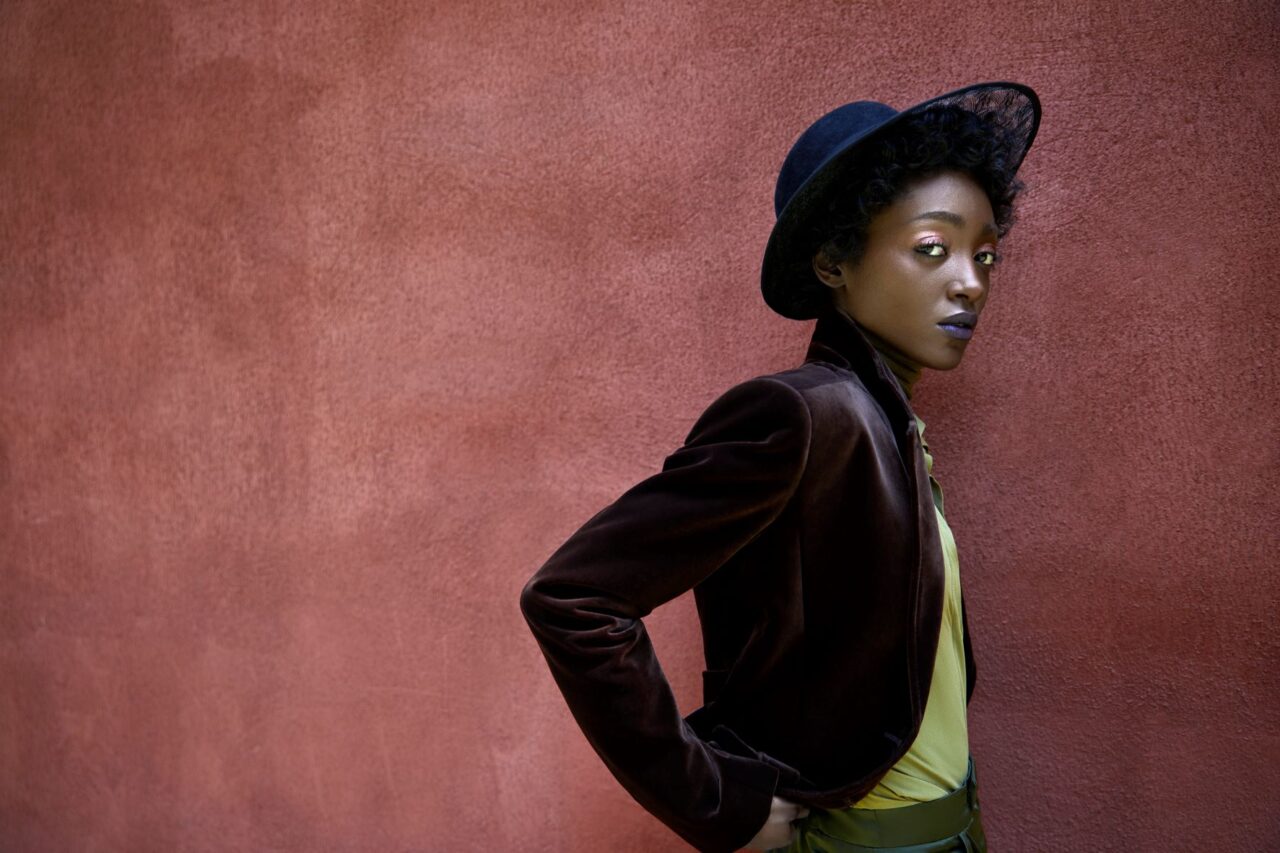 Female model looks a us as she's standing against a wall