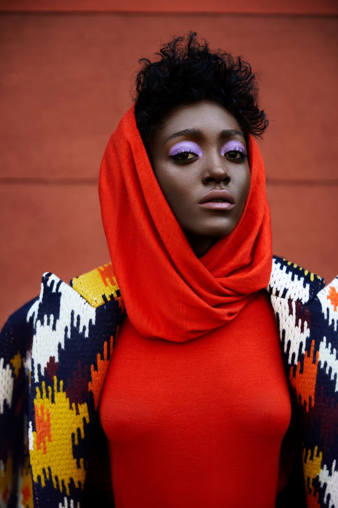 Woman wearing a bright red sweater and scarf, looking straight at the camera