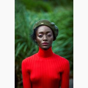 Female model wearing a bright red sweater and a bright Dior beret