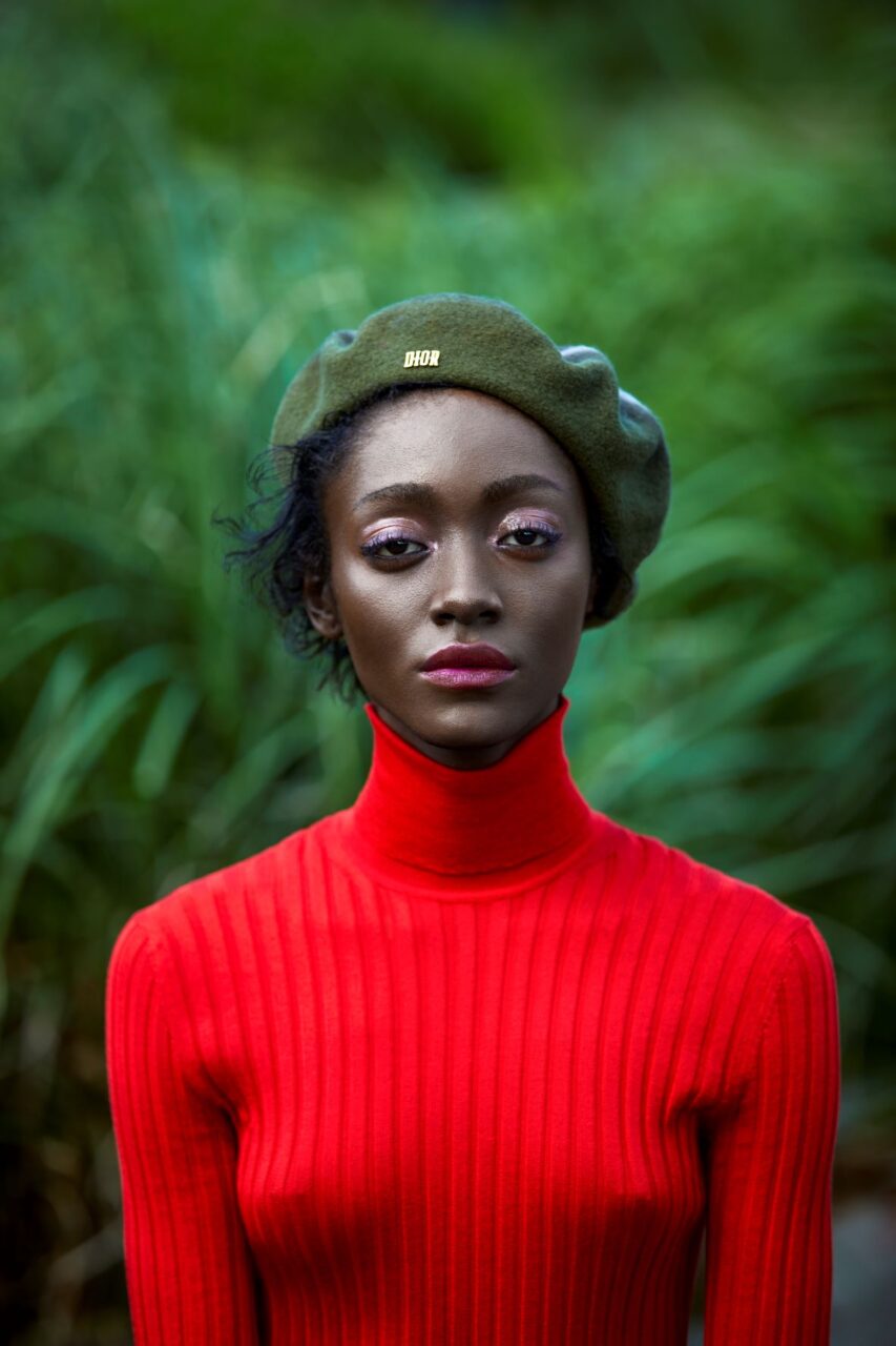 Female model wearing a bright red sweater and a bright Dior beret