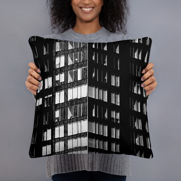 A woman holding a large square pillow with a photograph of a skyscraper façade