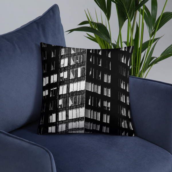 On a chair, a large square pillow with a photograph of a skyscraper façade