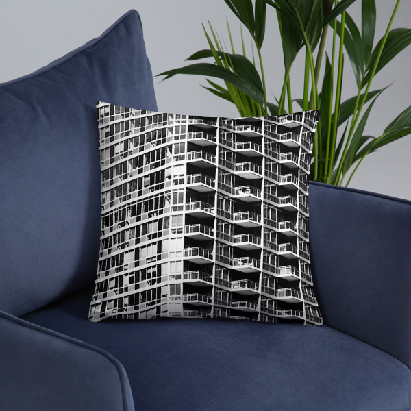 On a chair, a large square pillow with a photograph of a skyscraper façade