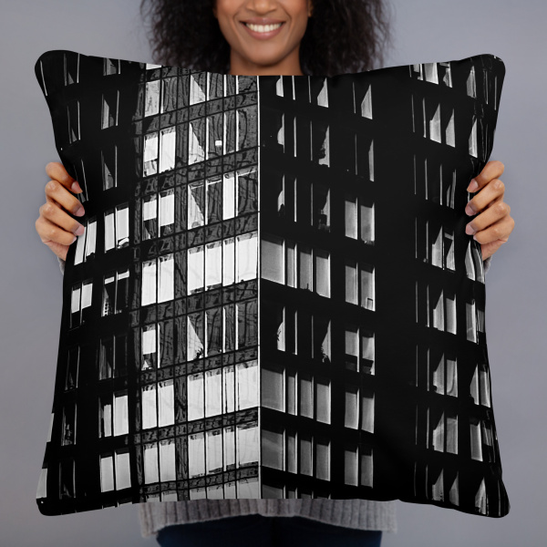A woman holding a large square pillow with a photograph of a skyscraper façade