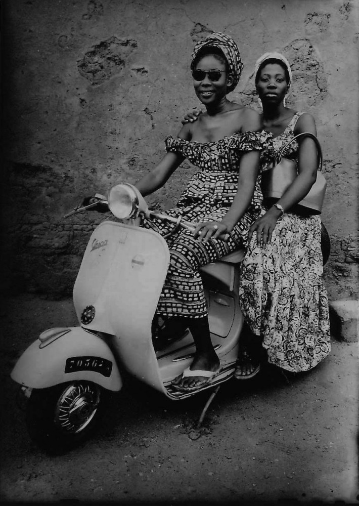 Portrait of two young Malian women sitting on a scooter