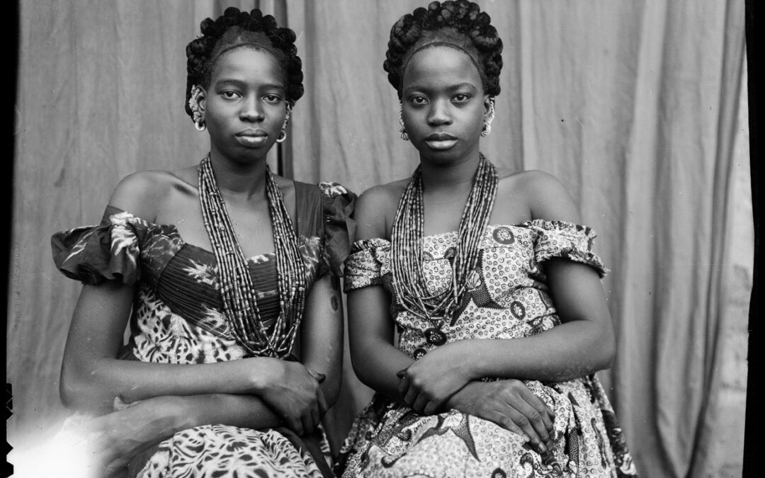 Formal portrait of two young African women, dressed in traditional dresses