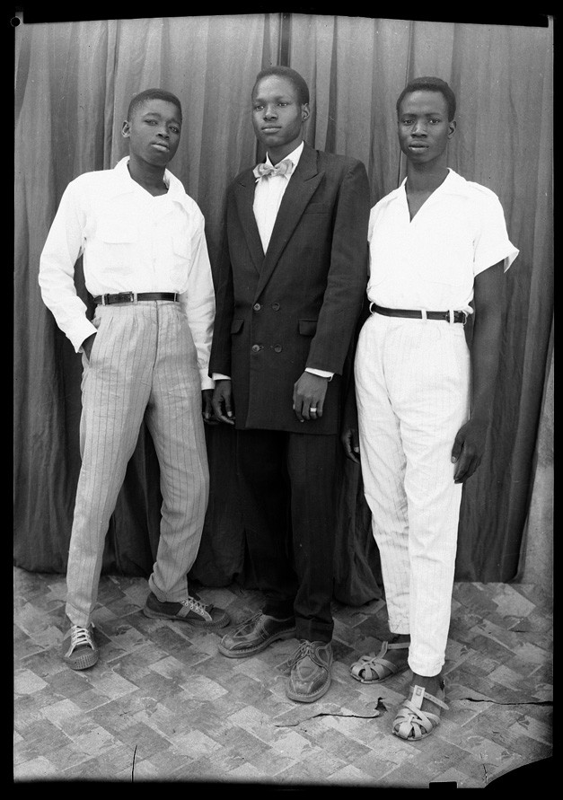 Portrait of three young Malian men, standing tall, dressed in suits