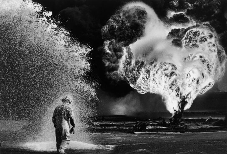 A lone worker walks among burning oil fields in the Kuwaiti desert