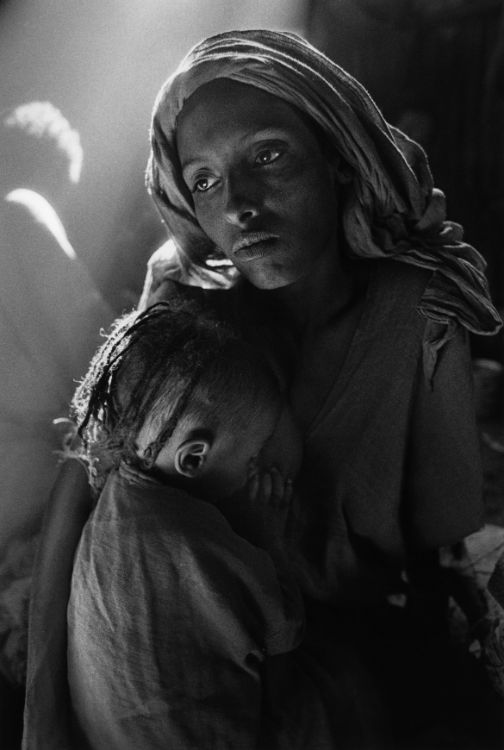 African mother holding her baby against a chest in a refugee camp