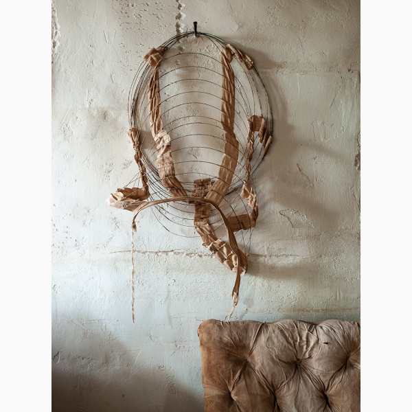 The metal remant of a 19th-century hooped skirt hangs against a plastered wall, with a couch under it
