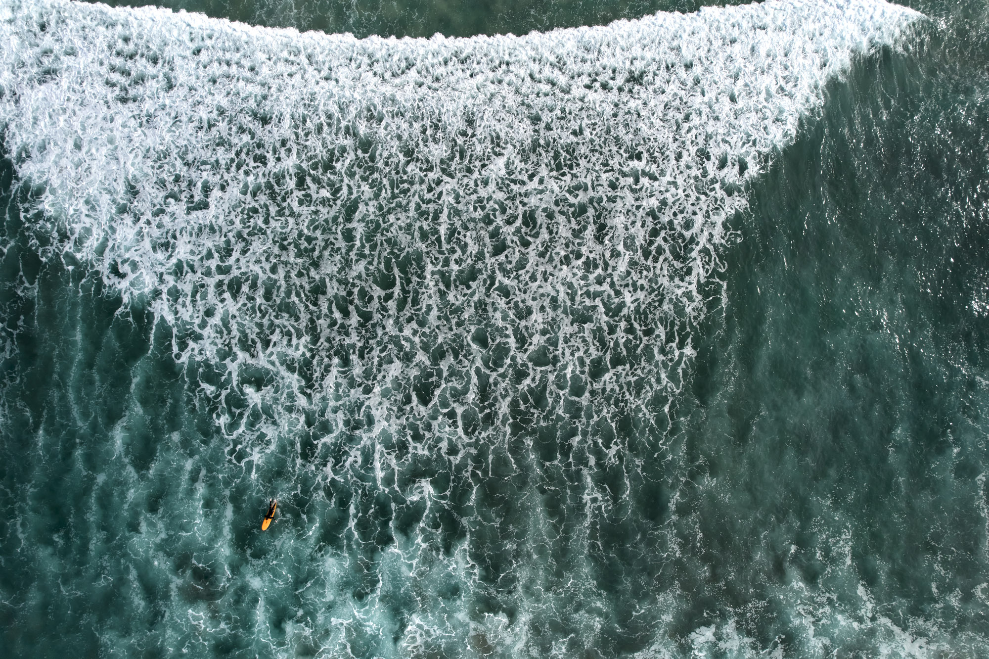 Limited edition print of an aerial photography of a surfer in front a large wave