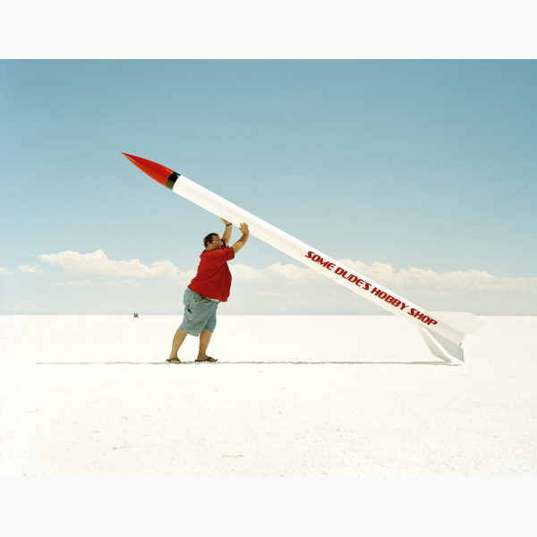 An overweight man lifts the rocket that he built to set it up for launching