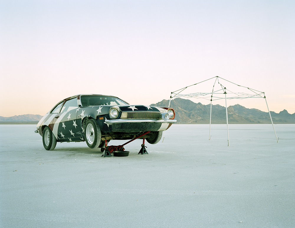 A racing car is raised for repair in the middle of a salt flat