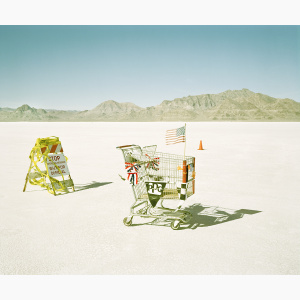 A shopping cart with an American flag and car and car racing signs on a salt flat
