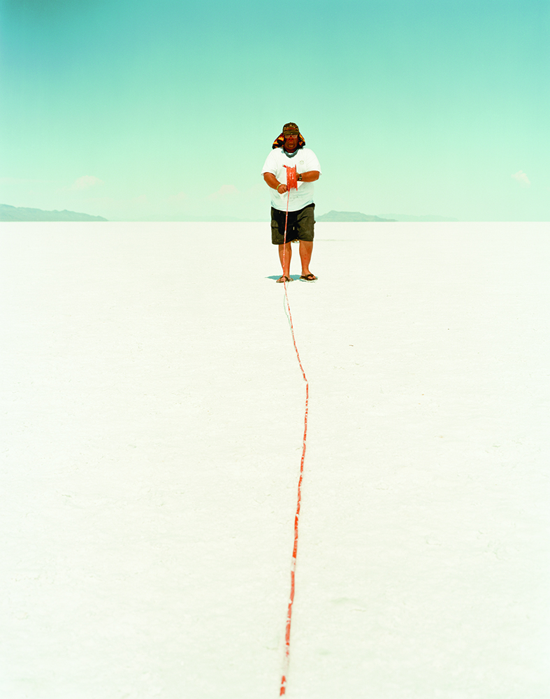 Man winding a spool in a desertic salt flat