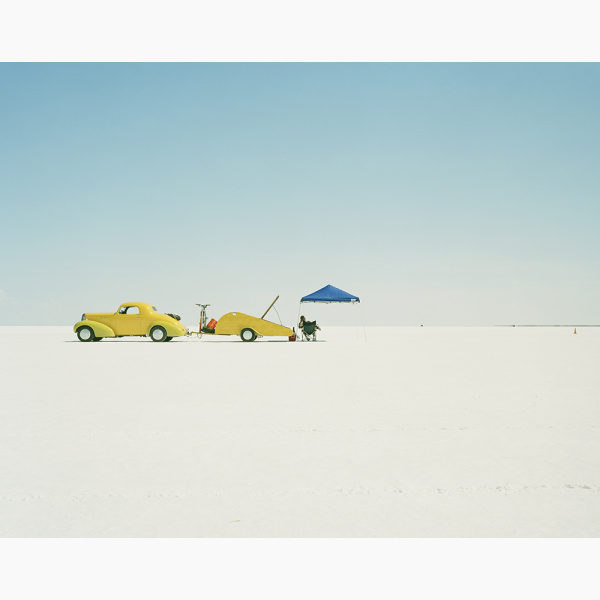 A yellow racing car stands on a salt flat