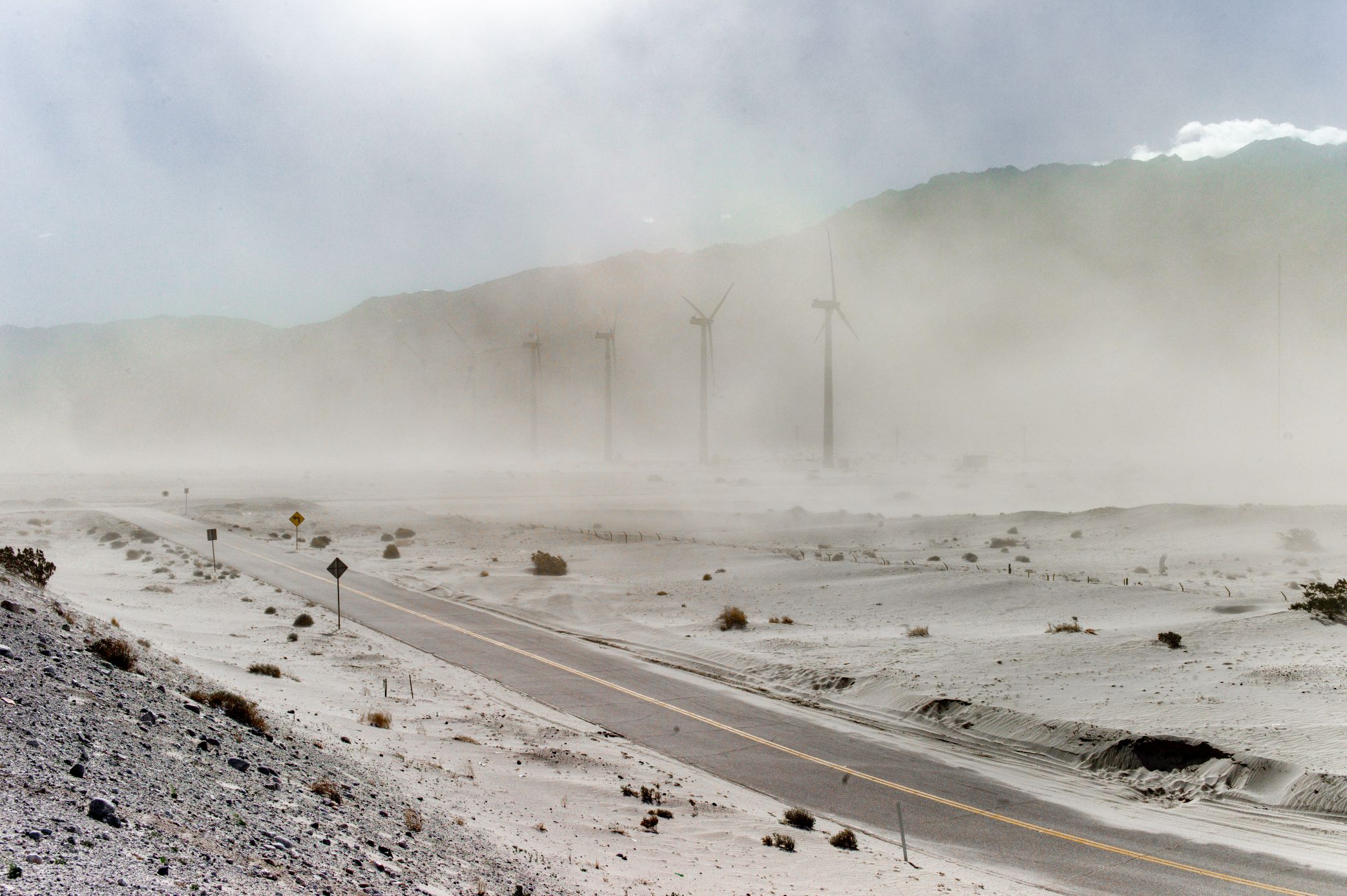 Limited edition print of a dusty desertic route with wind turbines in the distance