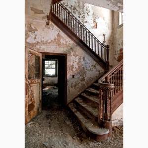 A grand staircase stands in an abandoned building